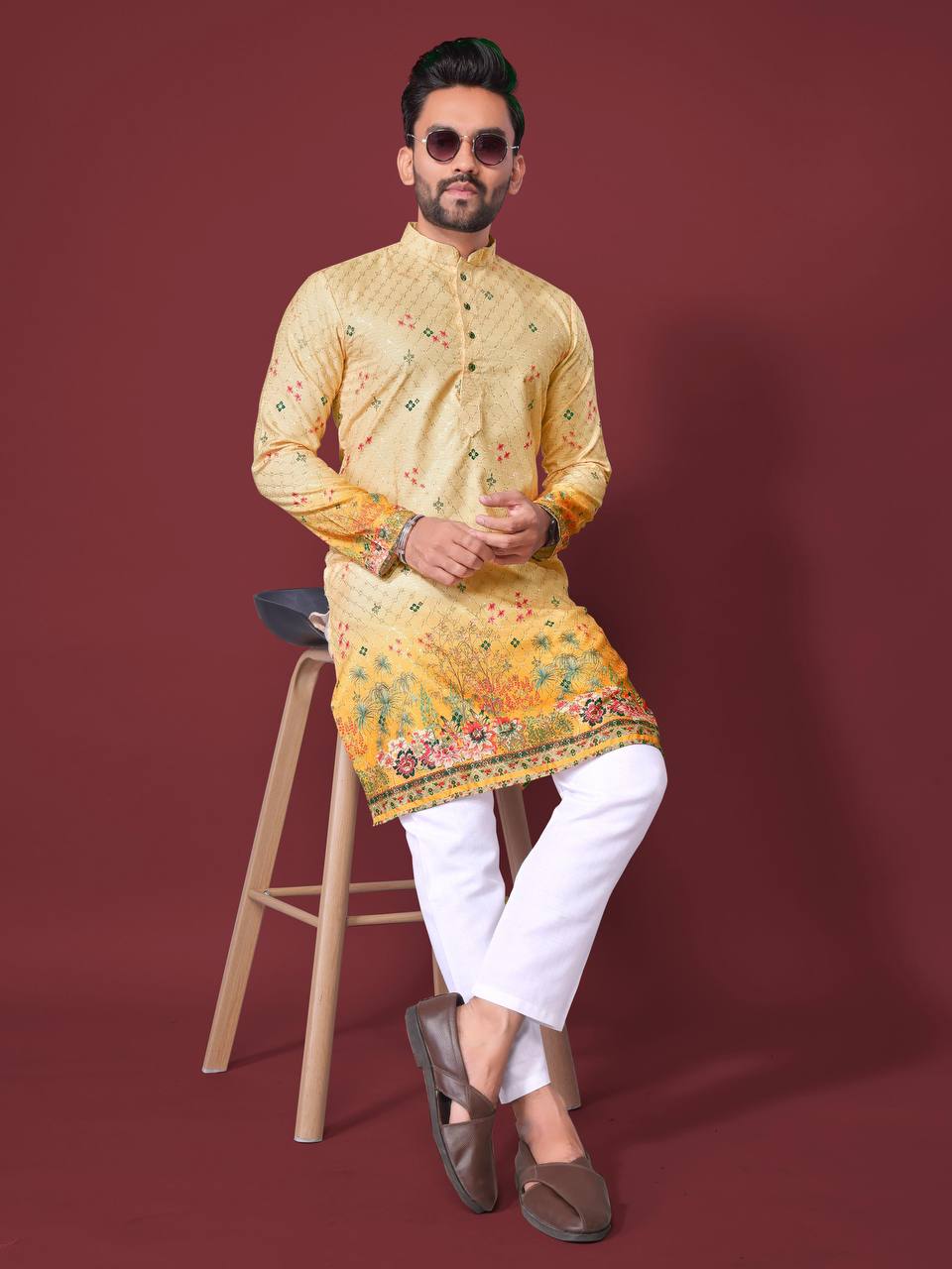 Man wearing a yellow embroidered kurta with floral designs paired with white pants and brown loafers